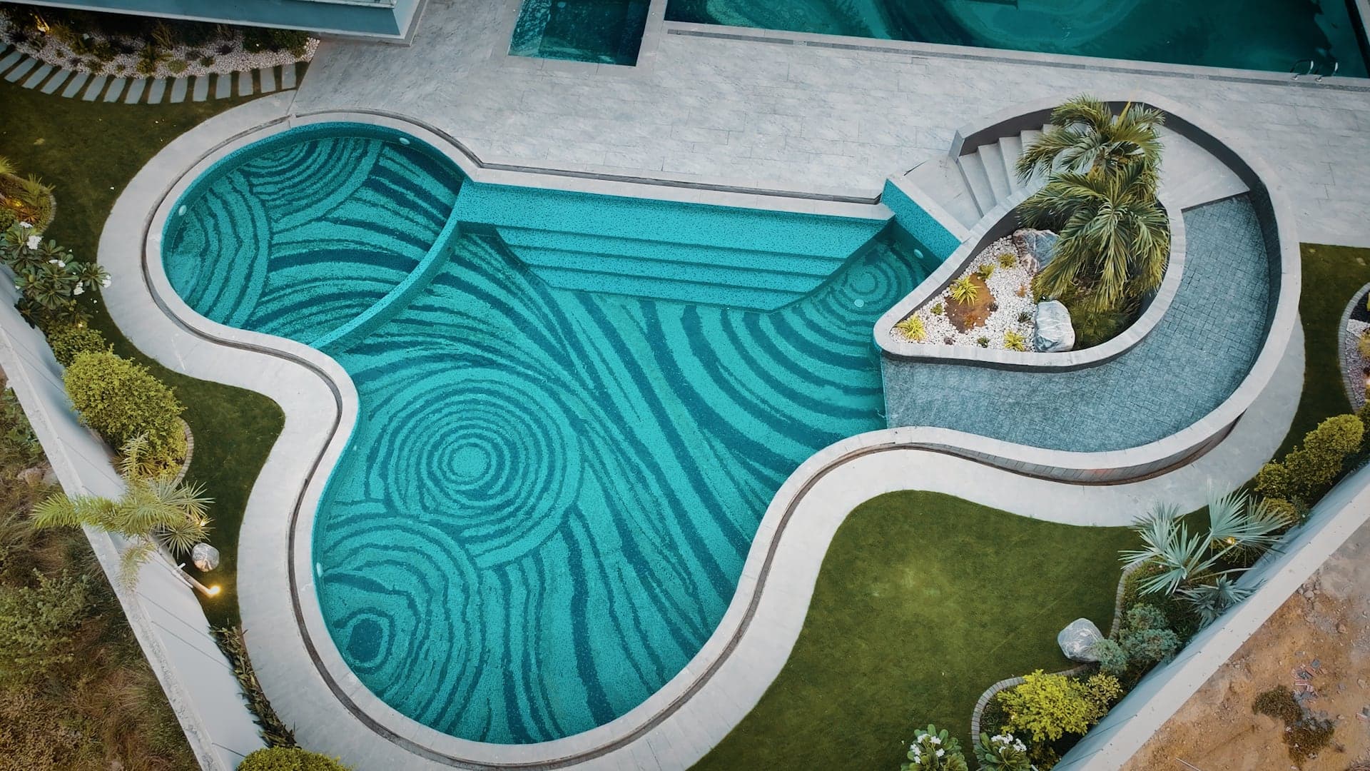 Free-form kids' leisure pool with swirl-pattern mosaic tiling and a landscaped rock garden at FHU Resorts Karachi