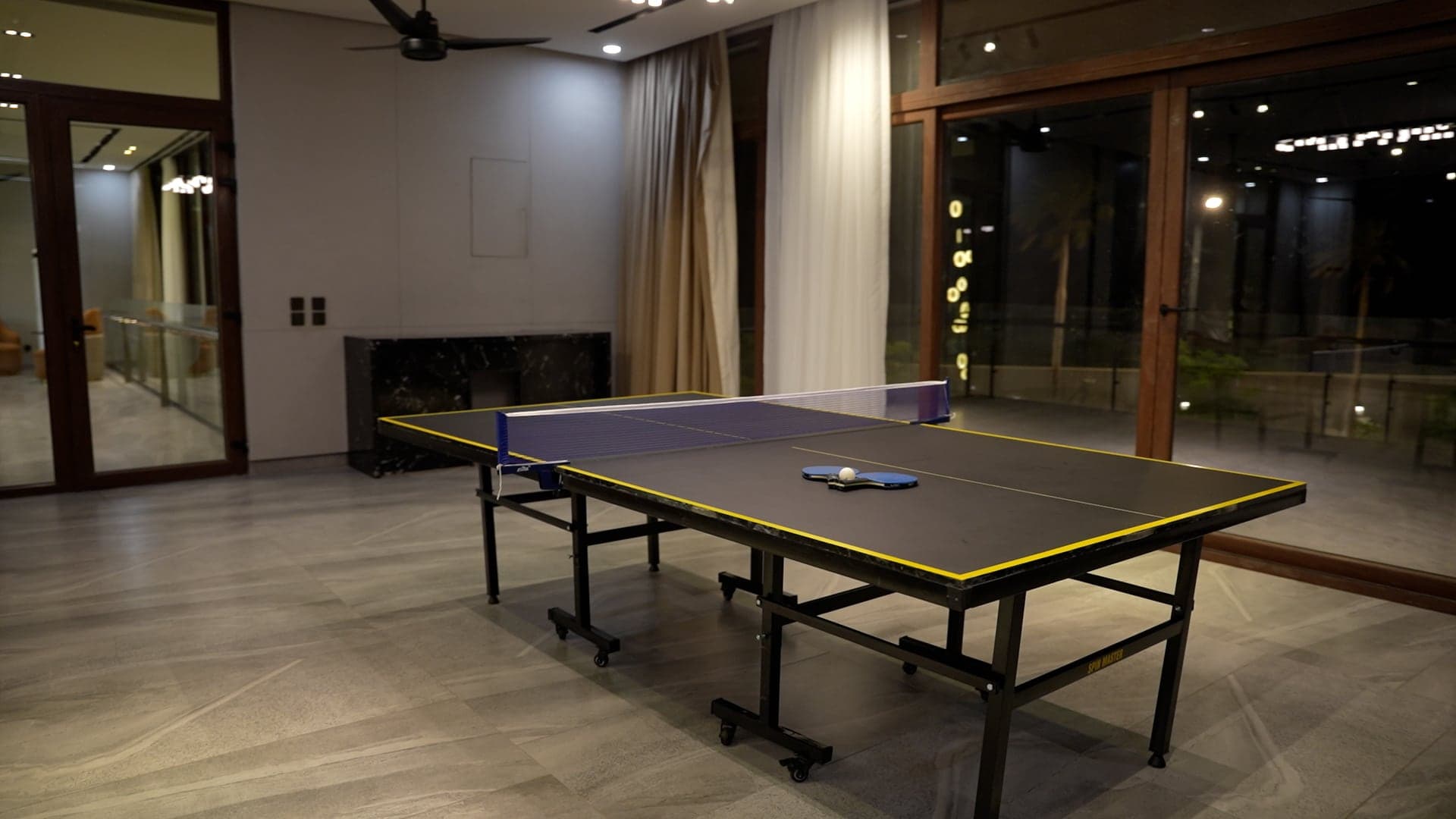 Table-tennis table beside floor-to-ceiling windows in the indoor games lounge at FHU Resorts Karachi