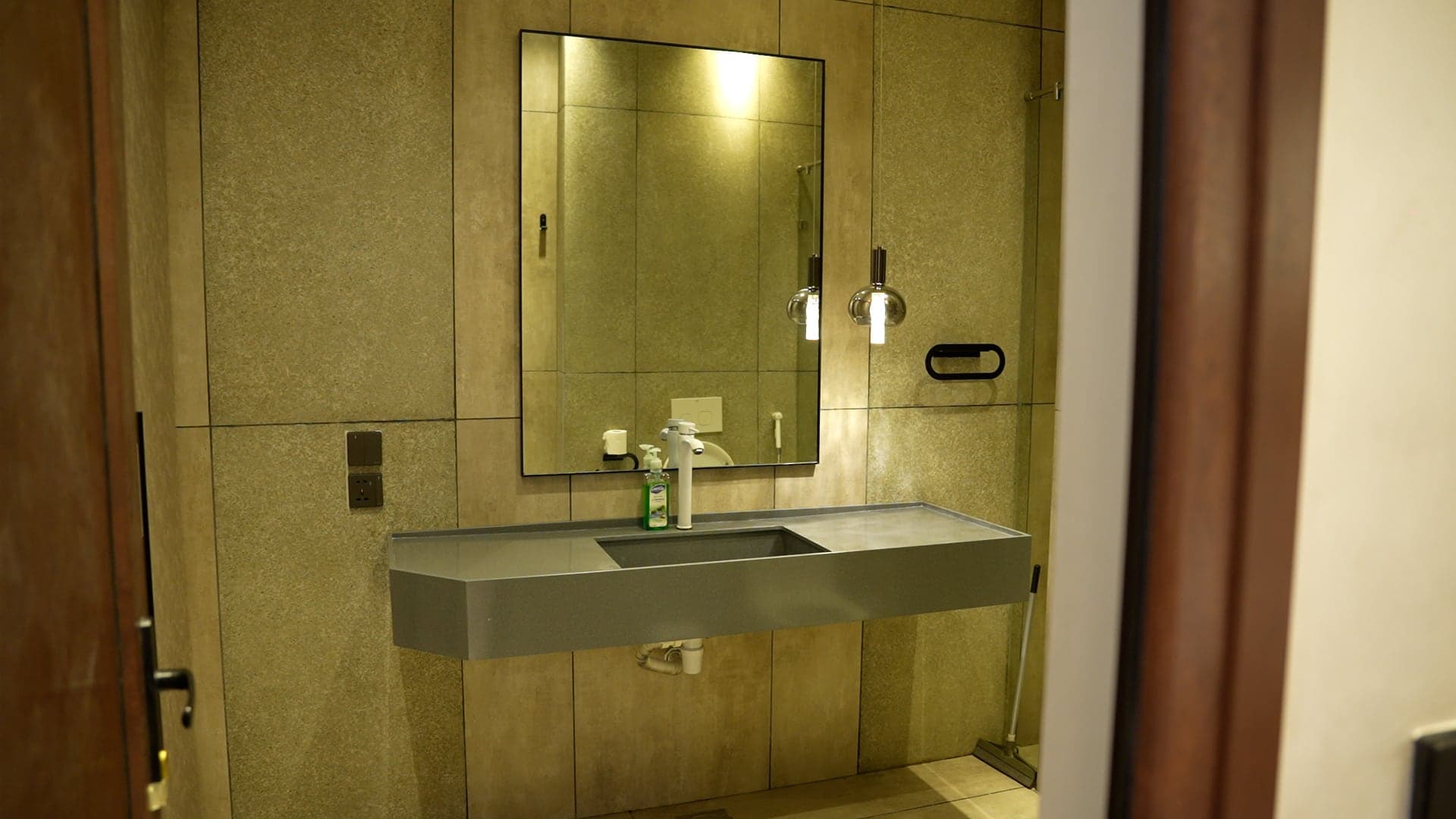 En-suite bathroom with a floating grey stone vanity and framed mirror under warm pendant lights at FHU Resorts Karachi