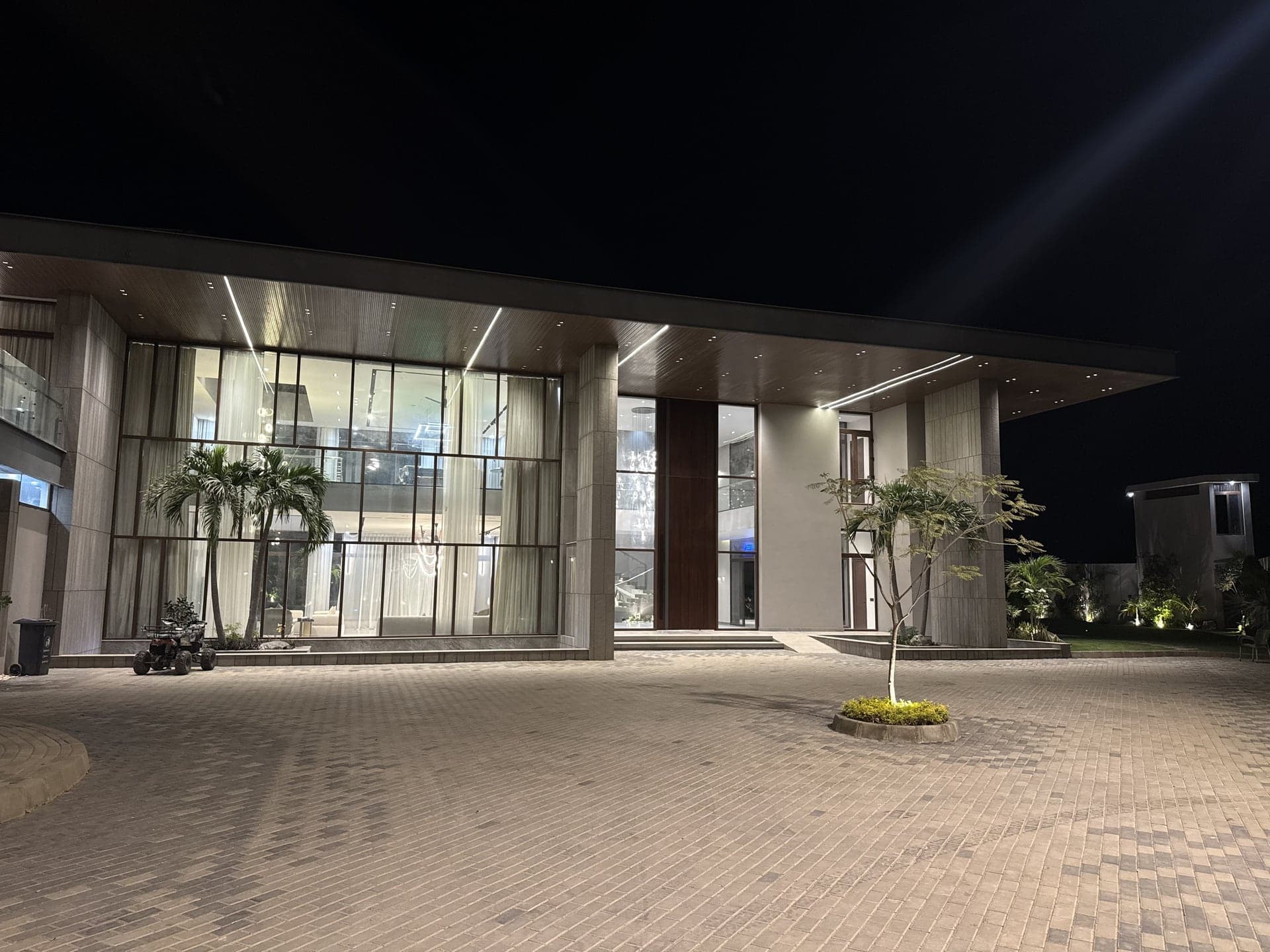 The illuminated glass villa facade and porte-cochere entrance lit up at night at FHU Resorts Karachi