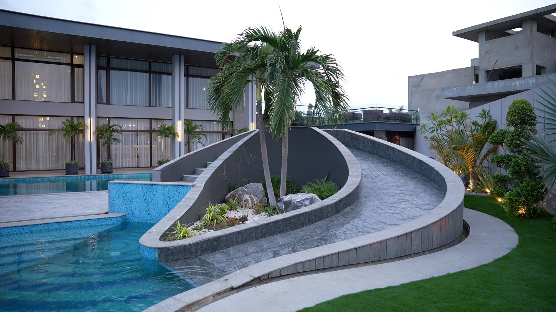 Free-form leisure pool with a raised palm-and-rock island and swirl mosaic at FHU Resorts Karachi