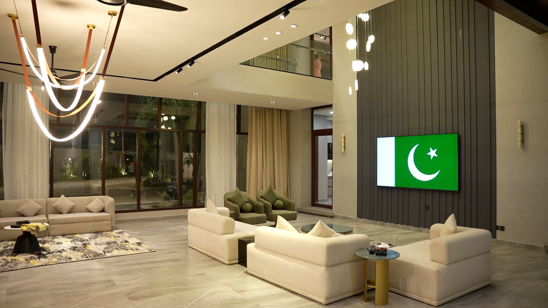 Double-height grand lounge with sculptural LED chandeliers, plush cream sofas and a feature TV wall at FHU Resorts Karachi