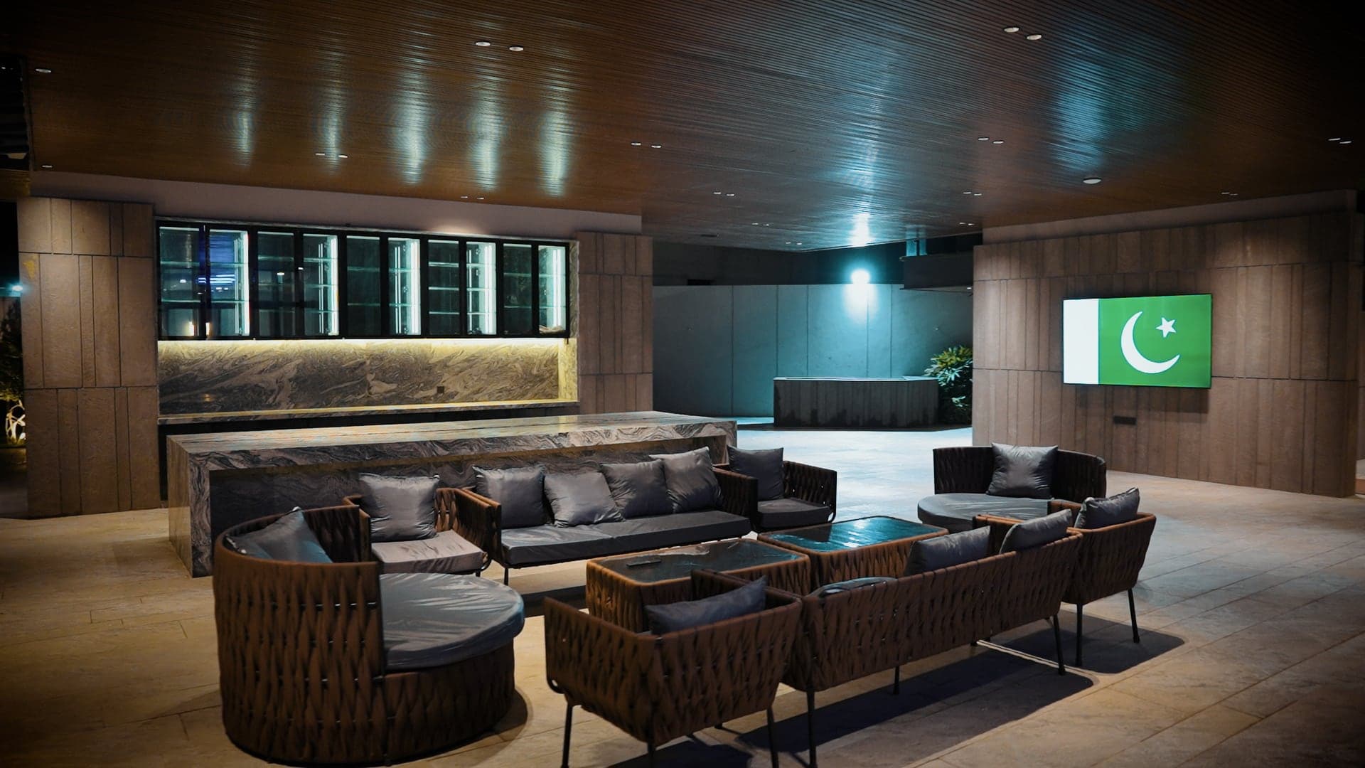 Covered open-air lounge with woven seating and a marble bar at FHU Resorts Karachi