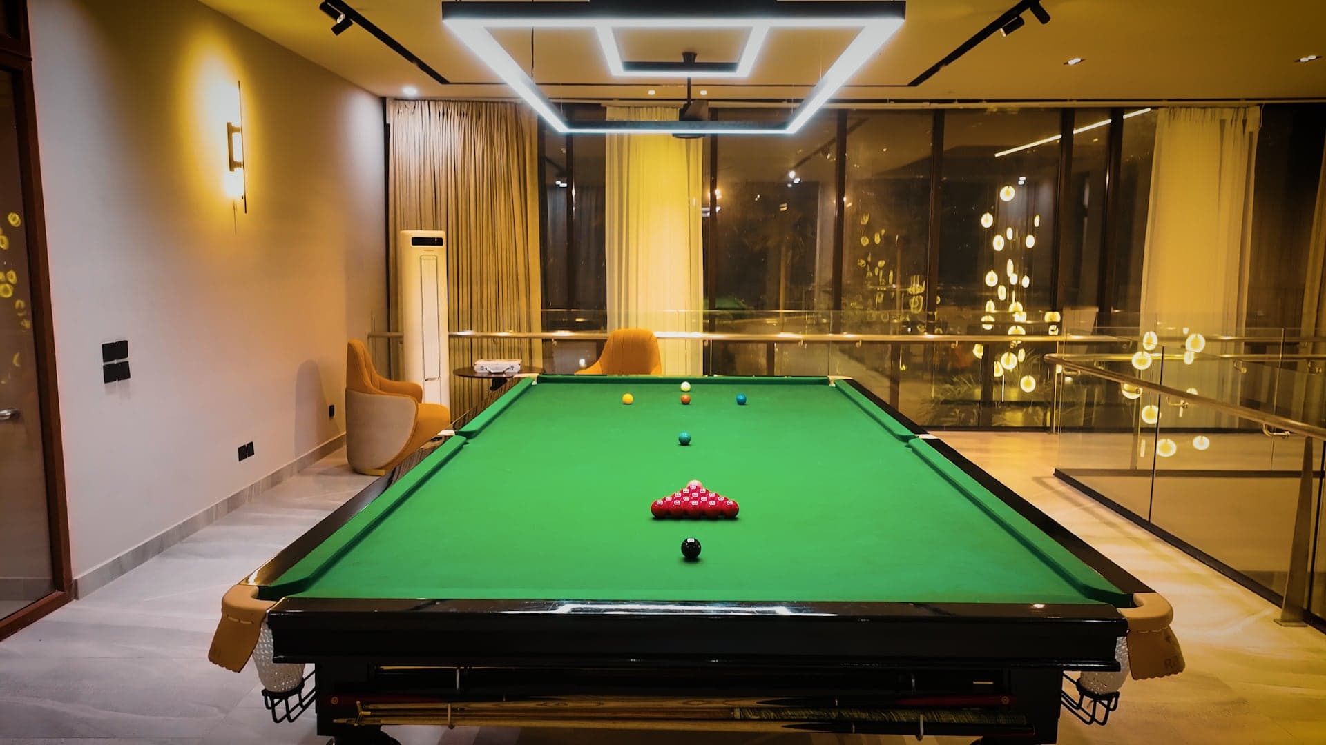 Full-size snooker table set for a frame beneath a rectangular LED chandelier at FHU Resorts Karachi